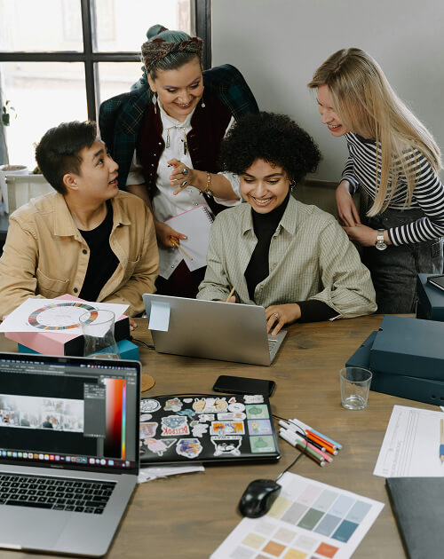 A team collaborating around a laptop in an open-plan office